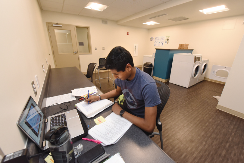 A student studies while doing laundry.